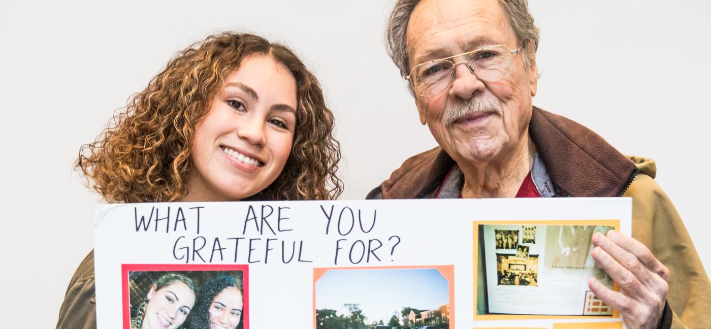 Younger woman and older man hold up an art project