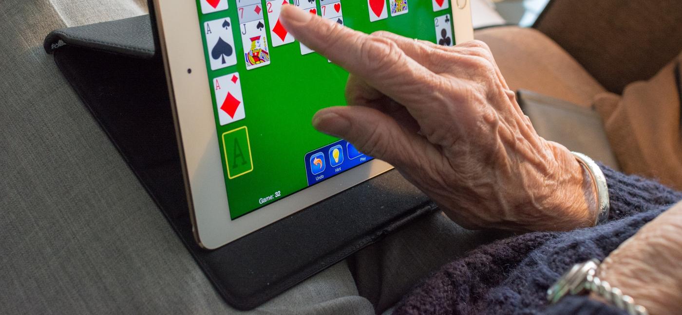 older person playing computer solitaire on a tablet