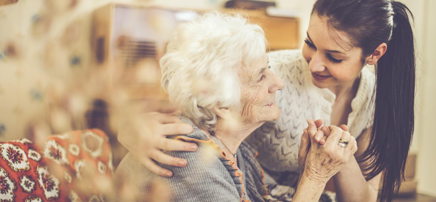 Older woman and care partner hold hands