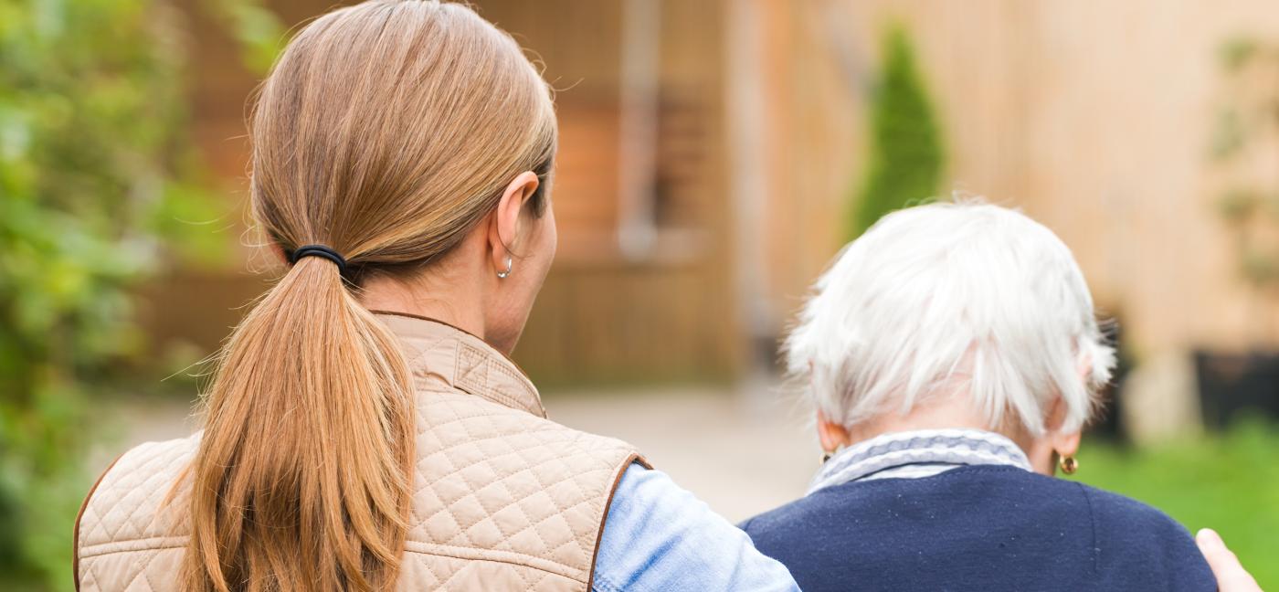 Young person walking with arm around old person