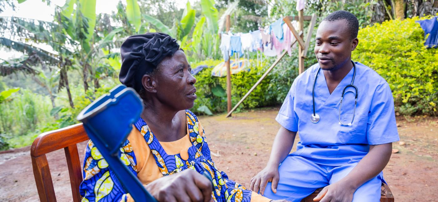 A sick old woman explaining her condition to a home visit doctor.
