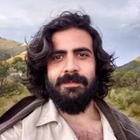 Headshot of Iván Caro outdoors with mountains in the background.