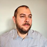 Stelios Zygouris wearing a light striped shirt and looking slightly to the side.
