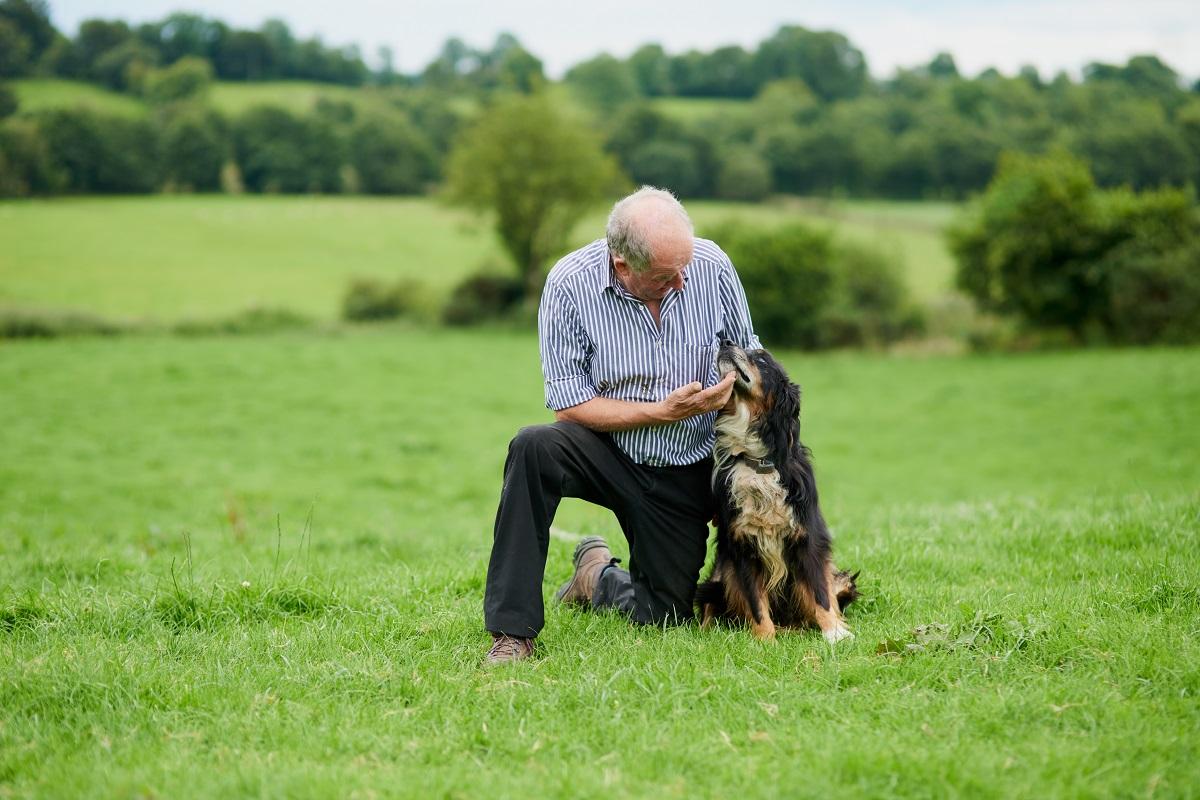 man with his dog in a green field