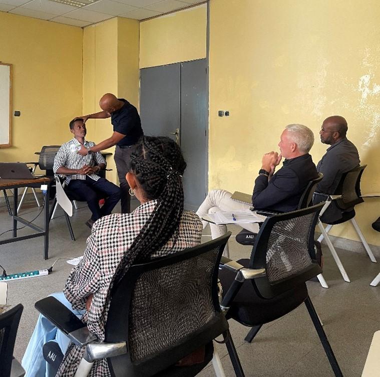 Clinical training session at Addis Ababa University with a facilitator demonstrating a neurological exam while colleagues observe.