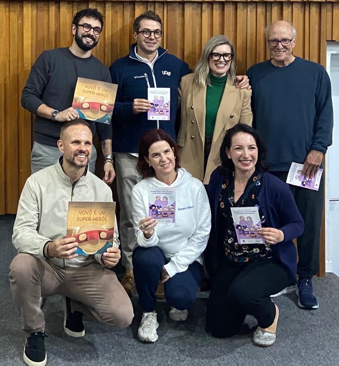 Atlantic Fellows and GBHI leaders pose together holding children's brain health books and educational booklets.