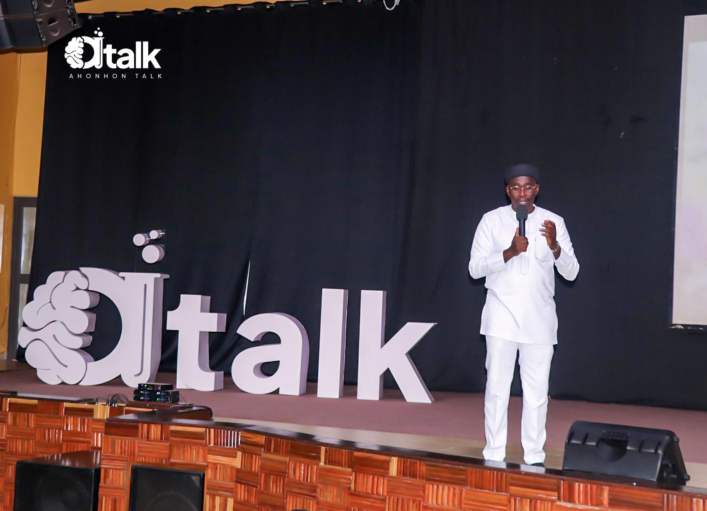 Mawuli Lawson speaks into a microphone on stage beside large Ahonhon Talk letters.
