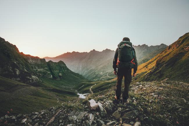Person hiking at sunset mountains with heavy backpack Travel Lifestyle wanderlust adventure concept summer vacations outdoor alone into the wild