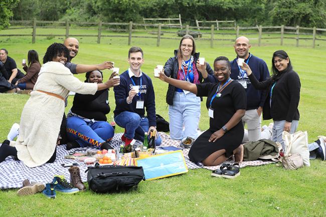 Atlantic Fellows gathered outdoors on blankets, raising cups together during a convening.