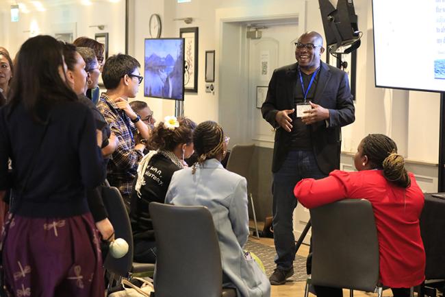 A fellow speaks to a small group of participants seated in a meeting room during the Oxford convening.