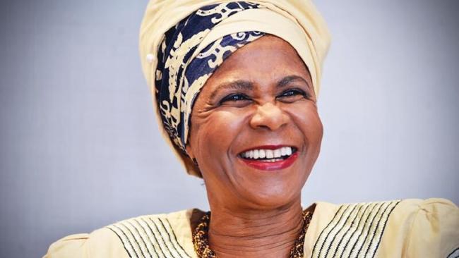 Portrait of Mamphela Ramphele smiling in a patterned headwrap and gold attire