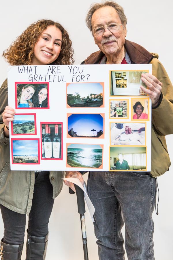 Younger woman and older man hold up an art project