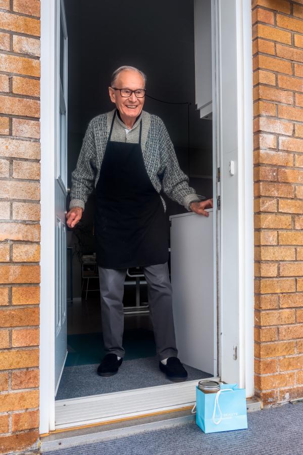 Older man standing in a doorway wearing an apron