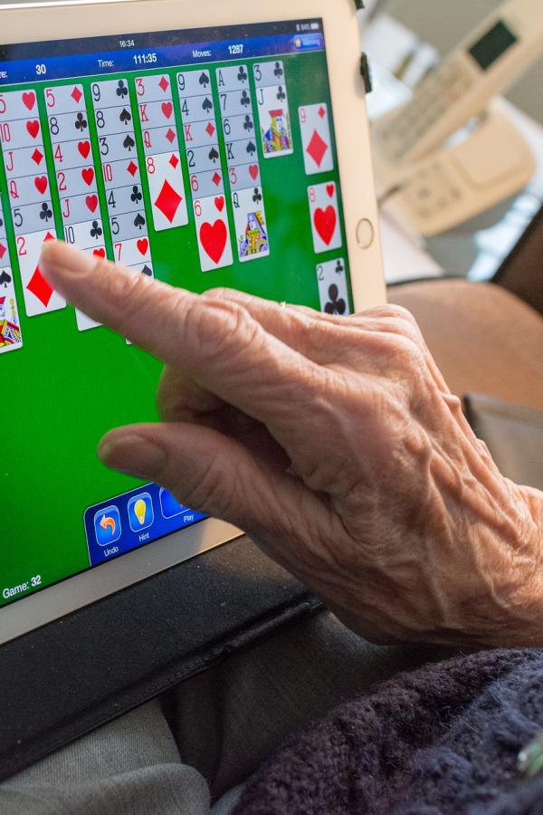 older person playing computer solitaire on a tablet