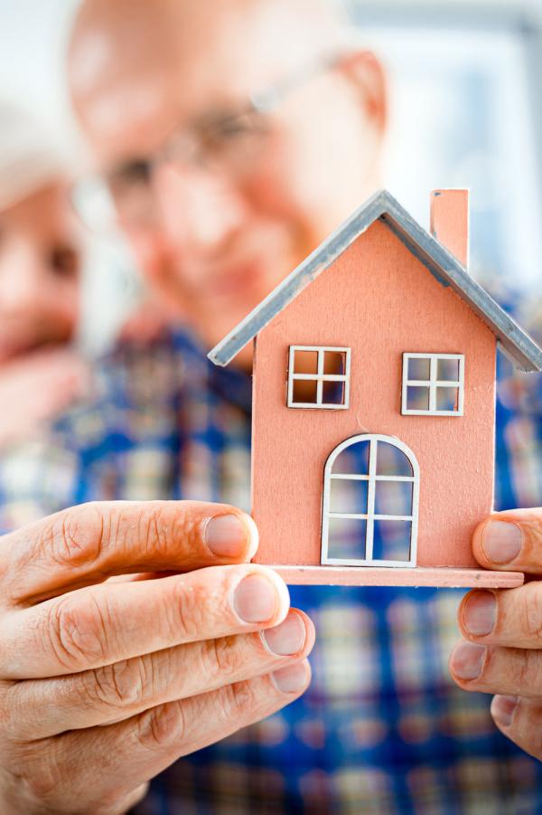 older couple holding a small model of a house