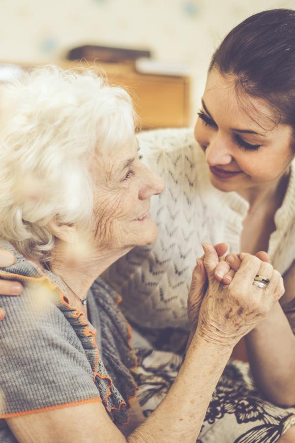 Older woman and care partner hold hands