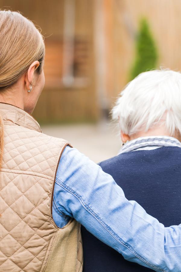 Young person walking with arm around old person