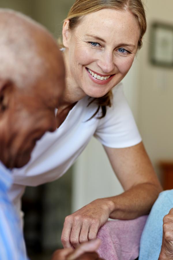 Happy female caretaker with senior people having coffee