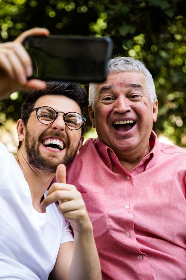 older and younger man taking selfie