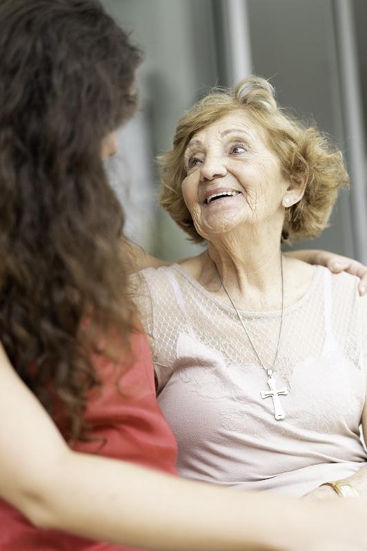 Granddaughter and grandmother sitting in bench outdoors
