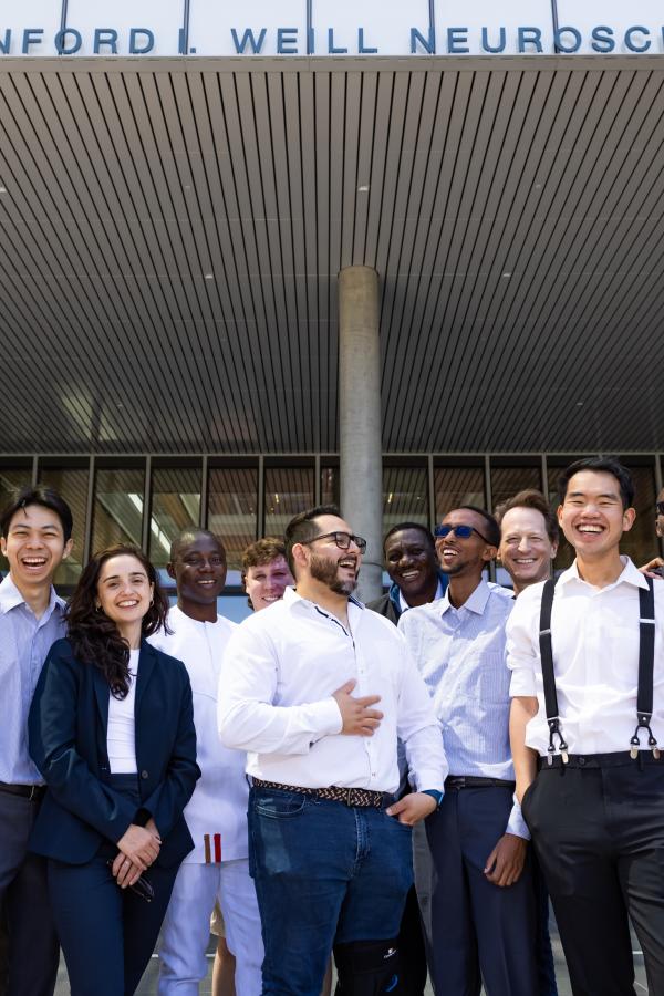 Atlantic Fellows for Equity in Brain Health Cohort 10 stand together laughing outside the UCSF Weill Neurosciences Building in San Francisco.