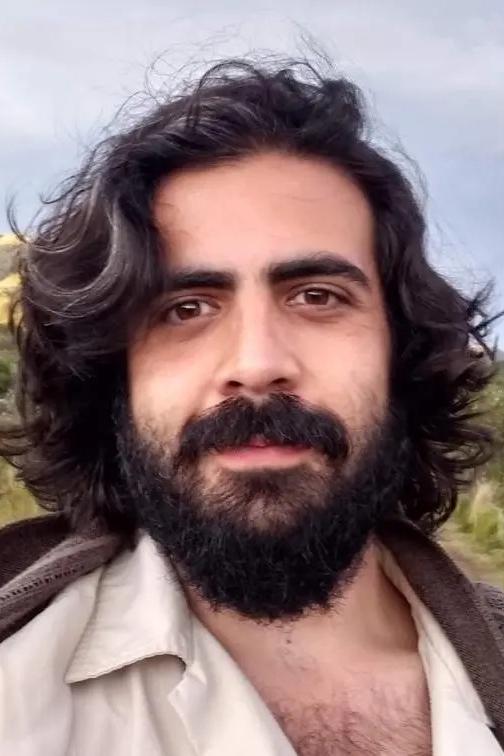 Headshot of Iván Caro outdoors with mountains in the background.