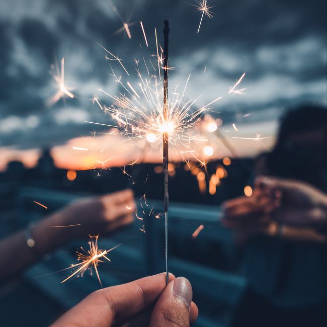 Three hands holding sparklers