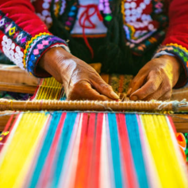 A person weaving a colorful cloth