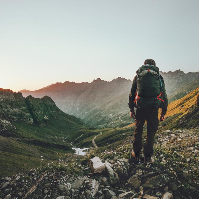 Person hiking at sunset mountains with heavy backpack Travel Lifestyle wanderlust adventure concept summer vacations outdoor alone into the wild