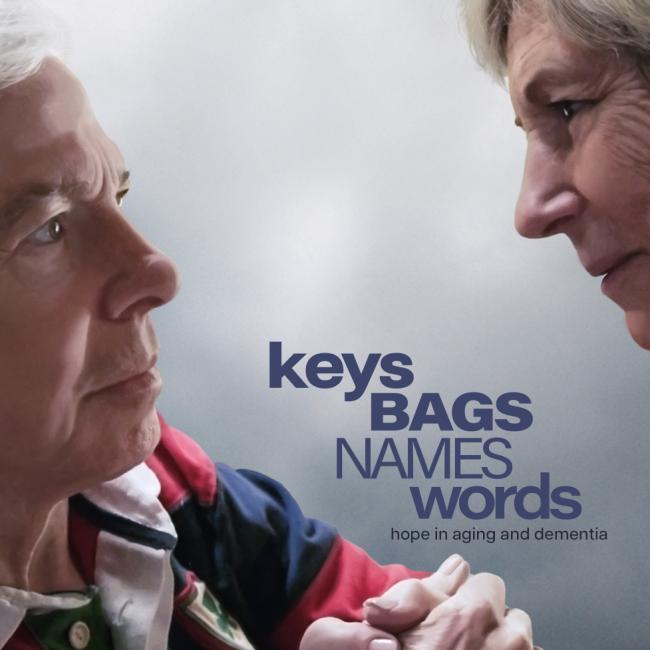 Two older adults sit face to face, holding hands, with the title “Keys Bags Names Words: hope in aging and dementia” overlaid.
