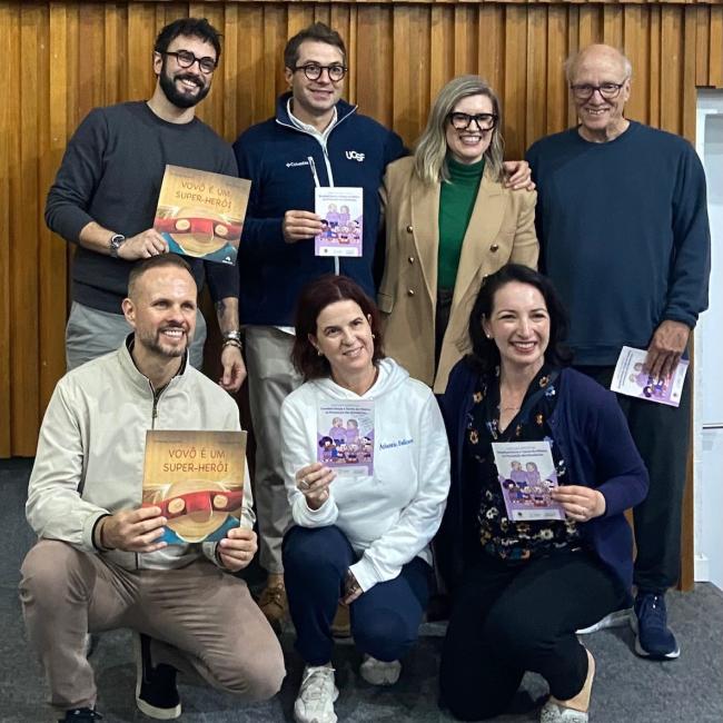 Atlantic Fellows and GBHI leaders pose together holding children's brain health books and educational booklets.
