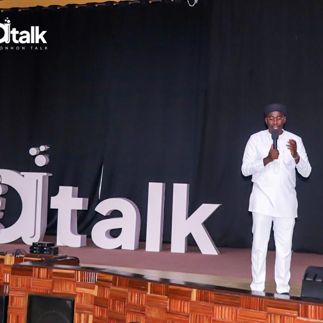 Mawuli Lawson speaks into a microphone on stage beside large Ahonhon Talk letters.