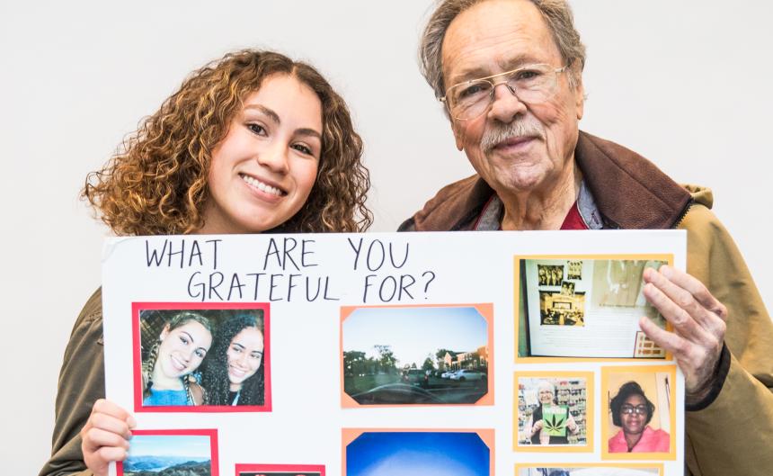 Younger woman and older man hold up an art project