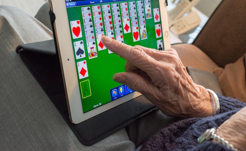 older person playing computer solitaire on a tablet