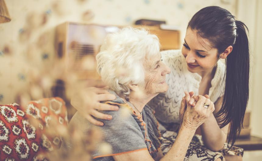 Older woman and care partner hold hands