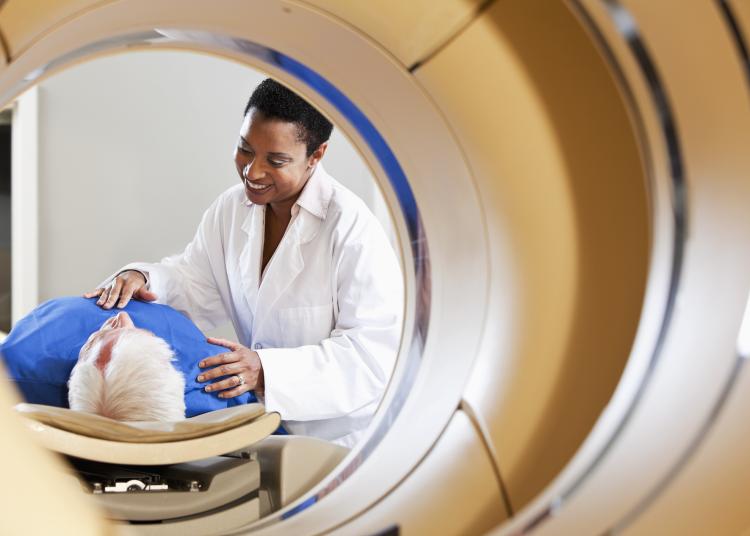 View of radiologist or technician with senior male patient through an integrated PET-CT scanner.