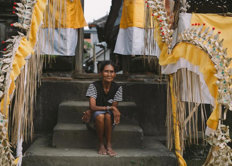 Older woman seated on steps arms folded looking into camera
