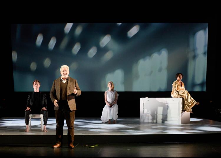 Four actors perform on stage during the UnRavelled play at the event, with soft lights and designs projected behind them.