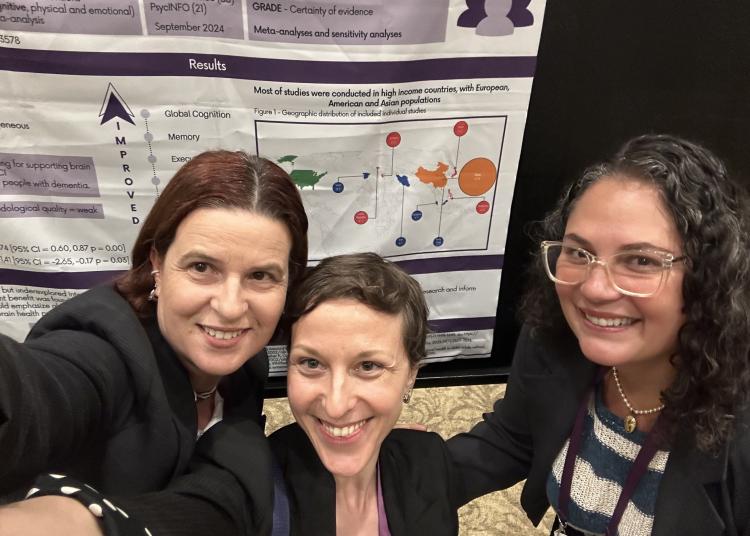 Three researchers smile in front of a scientific poster about dance and brain health.