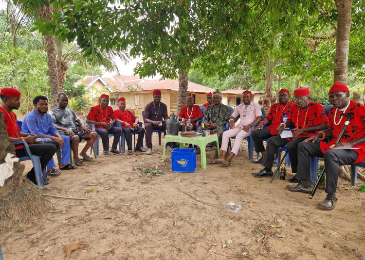 A group of community members and leaders sit together outdoors in Southeast Nigeria, engaged in discussion as part of a community health and dementia awareness initiative.