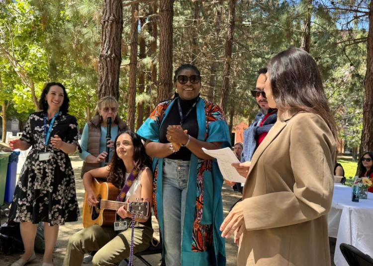 Participants gather outdoors along Feeney Way at UCSF during the GBHI 10-year anniversary celebration, with music, conversation, and community activities beneath a grove of trees.