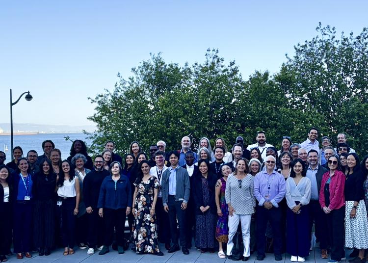 Atlantic Fellows, faculty, staff, and partners pose for a group photo overlooking San Francisco Bay during an anniversary community dinner.