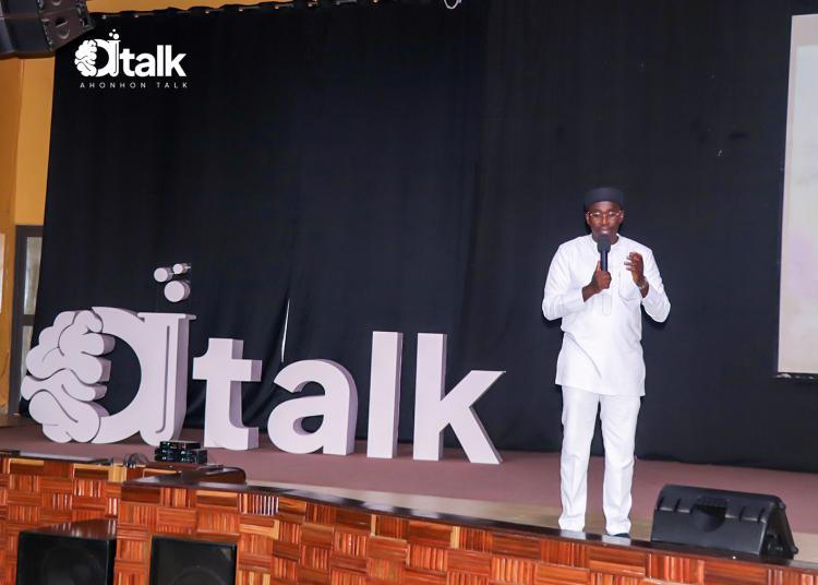 Mawuli Lawson speaks into a microphone on stage beside large Ahonhon Talk letters.