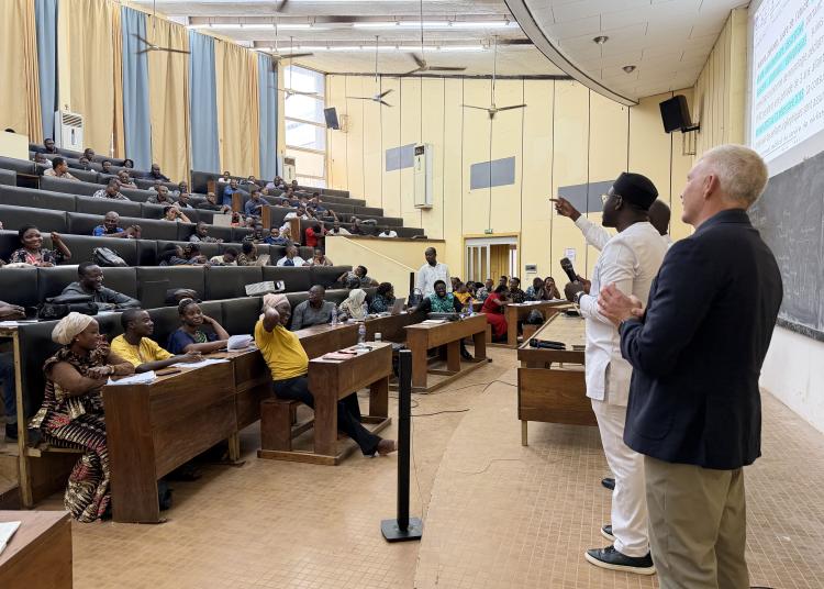 Mawuli Lawson and Victor Valcour speak at the front of a lecture hall filled with medical interns at the University of Lomé.