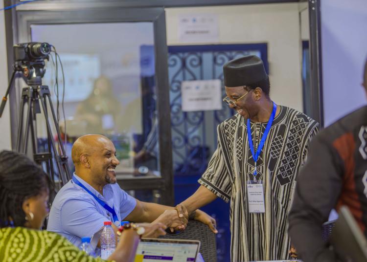 Yared Zewde and Alfred Njamnshi smile and shake hands during the seminar.