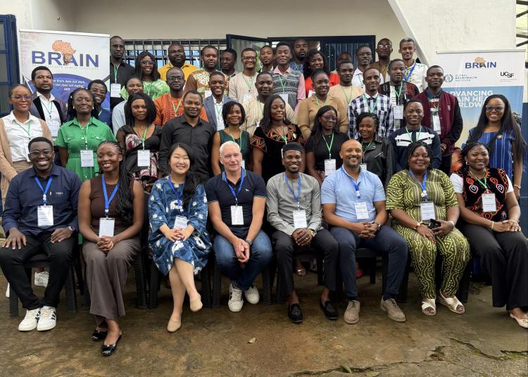 Seminar participants and speakers pose together outside the venue, flanked by BRAIN and GBHI banners.